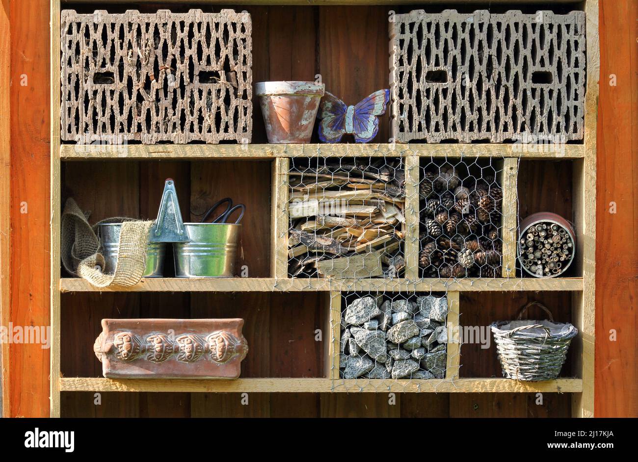 Shelf with insect hotel and garden utensils Stock Photo