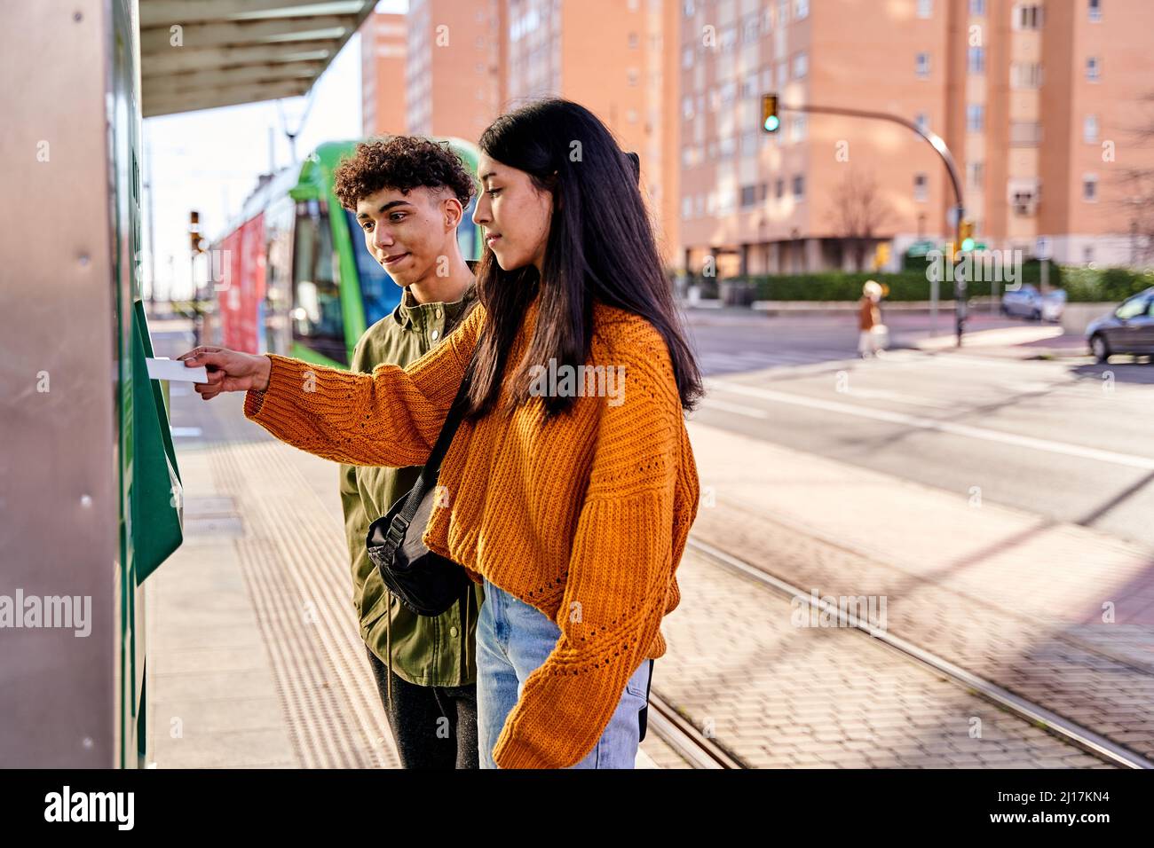 teenage couple buying tram tickets with their credit cards Stock Photo