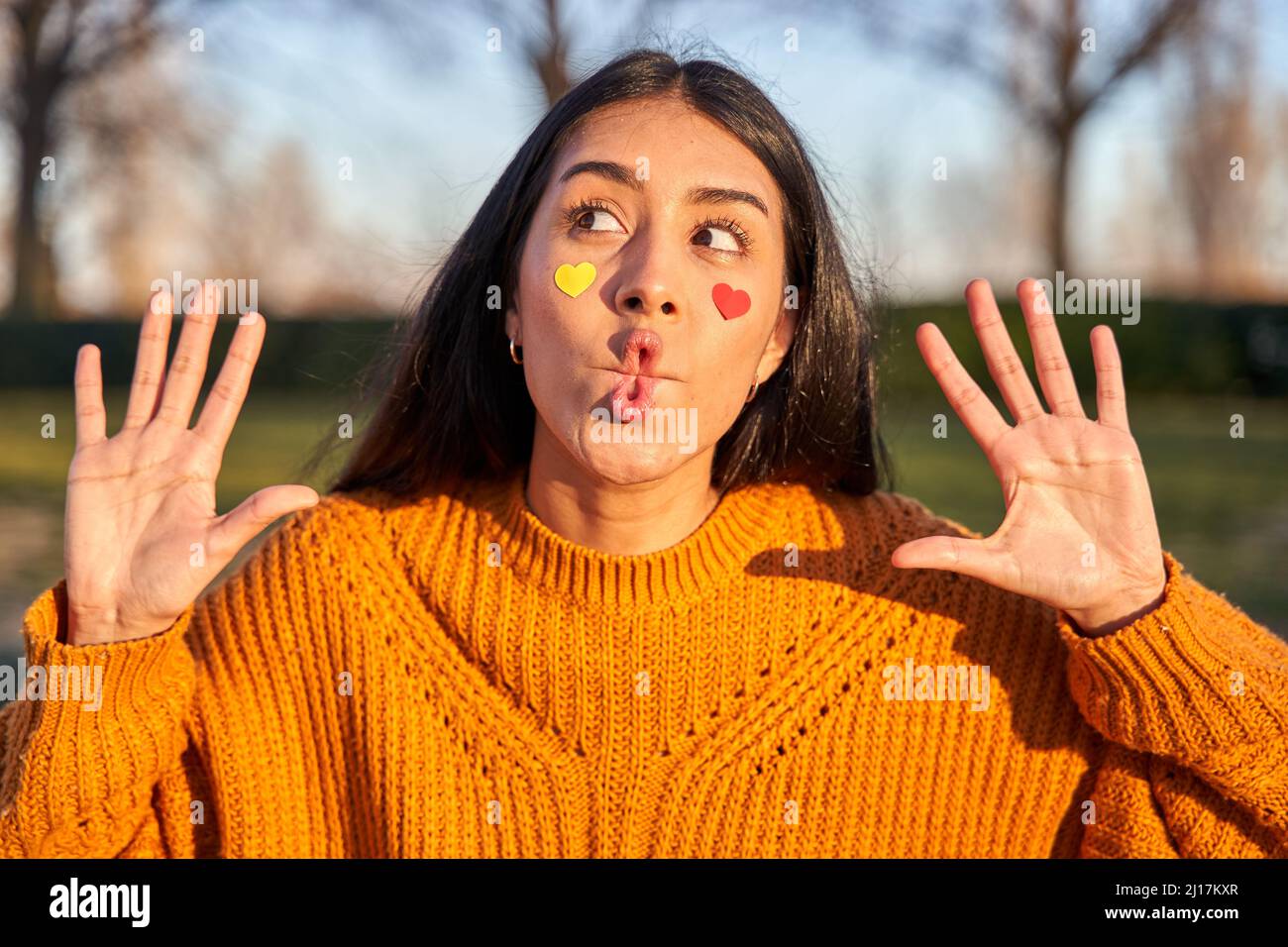 Photo of funny brunette haired young woman makes fish lips tries to amuse someone dressed in casual yellow sweater during free time Stock Photo