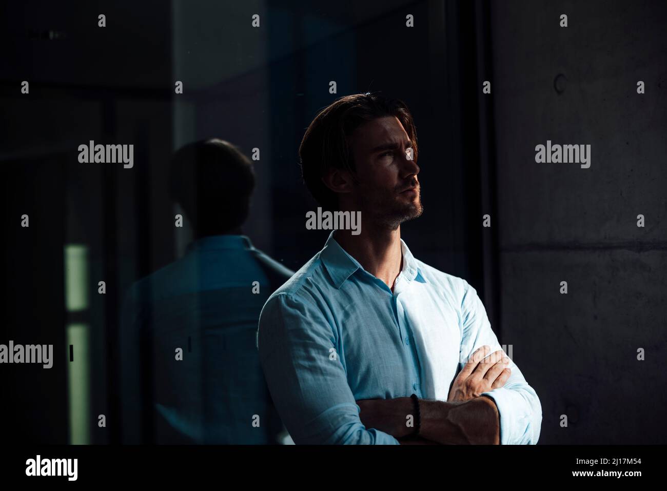 Businessman standing with arms crossed in front of glass wall Stock ...