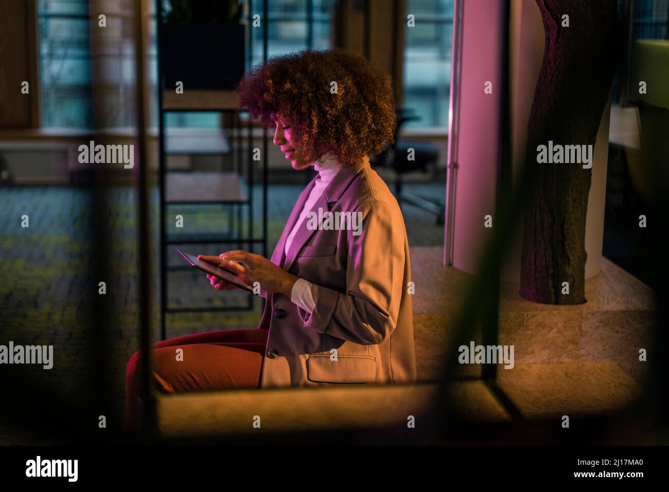 Businesswoman using tablet computer in illuminated office Stock Photo