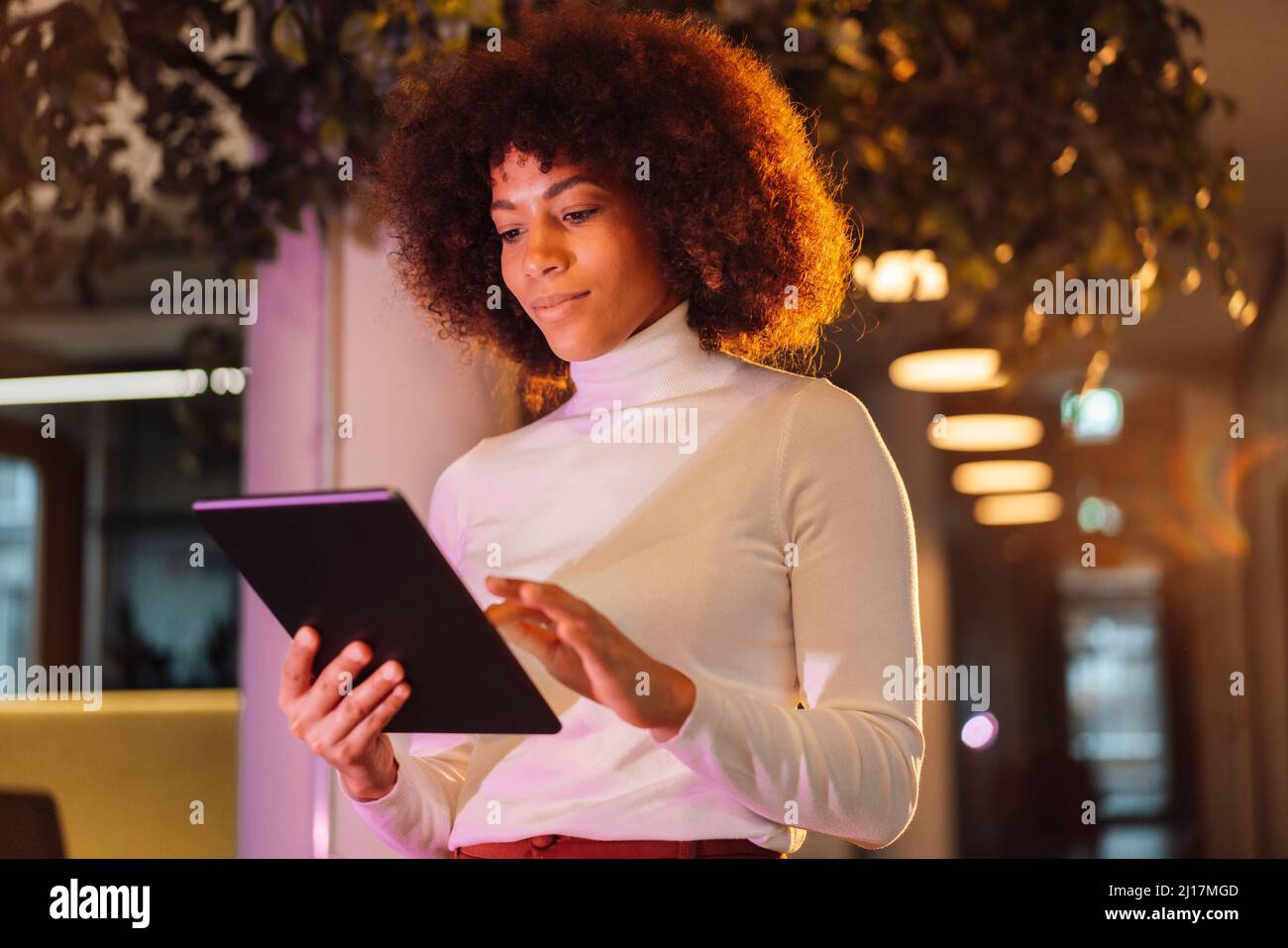 Businesswoman using tablet computer at illuminated work place Stock Photo