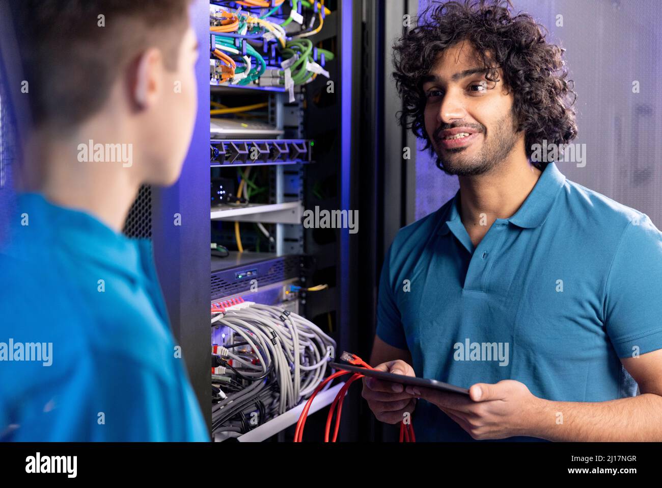 IT technician discussing with trainee in server room at industry Stock Photo