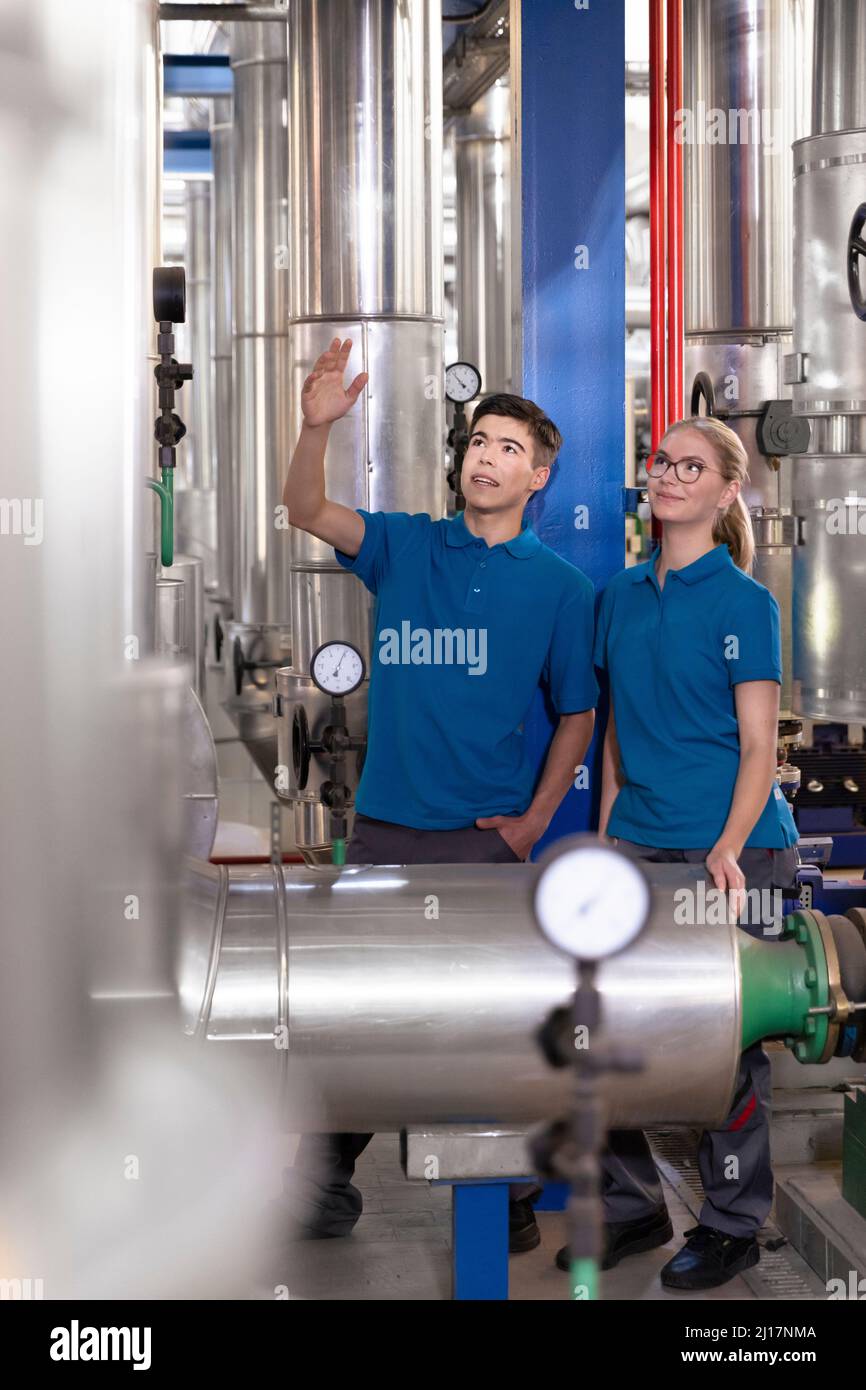 Technician showing machine pipe to colleague in industry Stock Photo