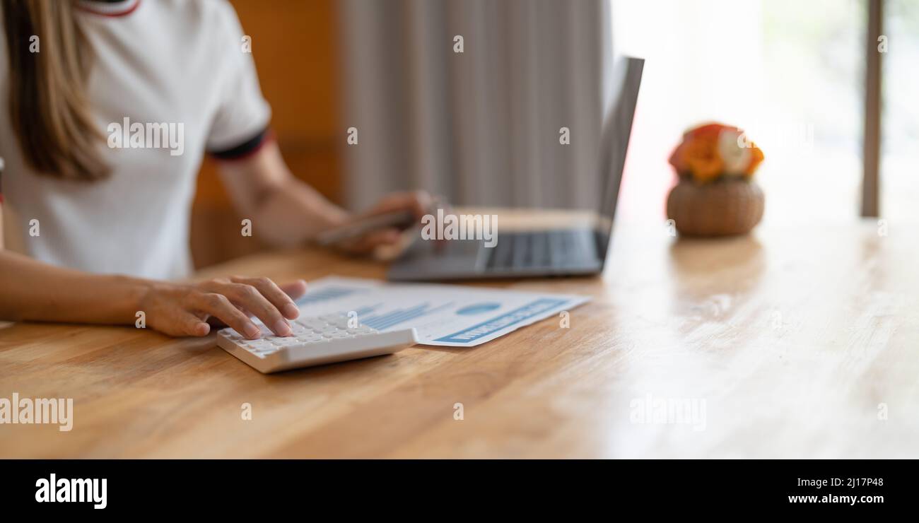 Close up Business woman using calculator and laptop for do math finance on wooden desk in office and business working background, tax, accounting Stock Photo