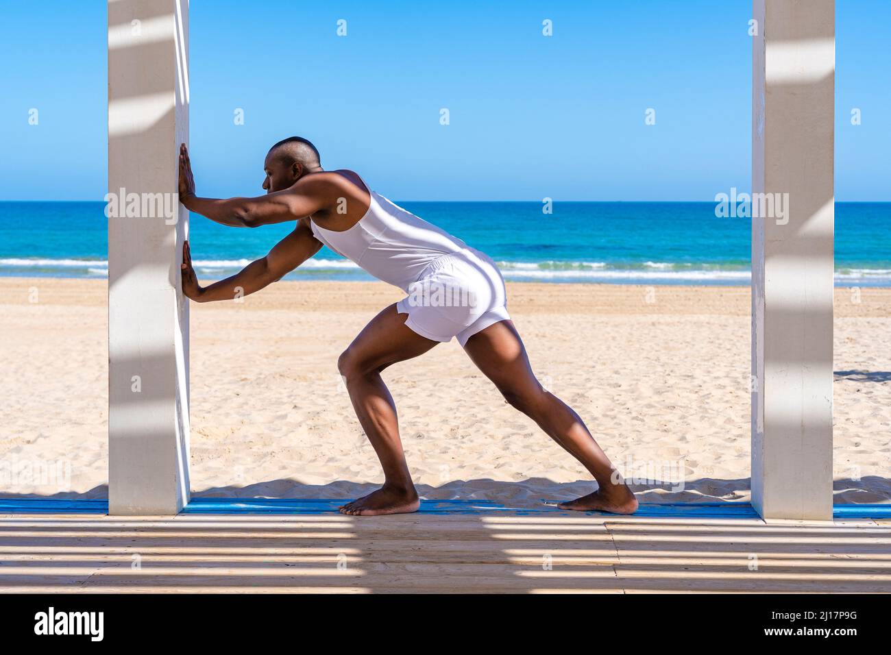 Sportsperson practicing stretching exercise at beach Stock Photo