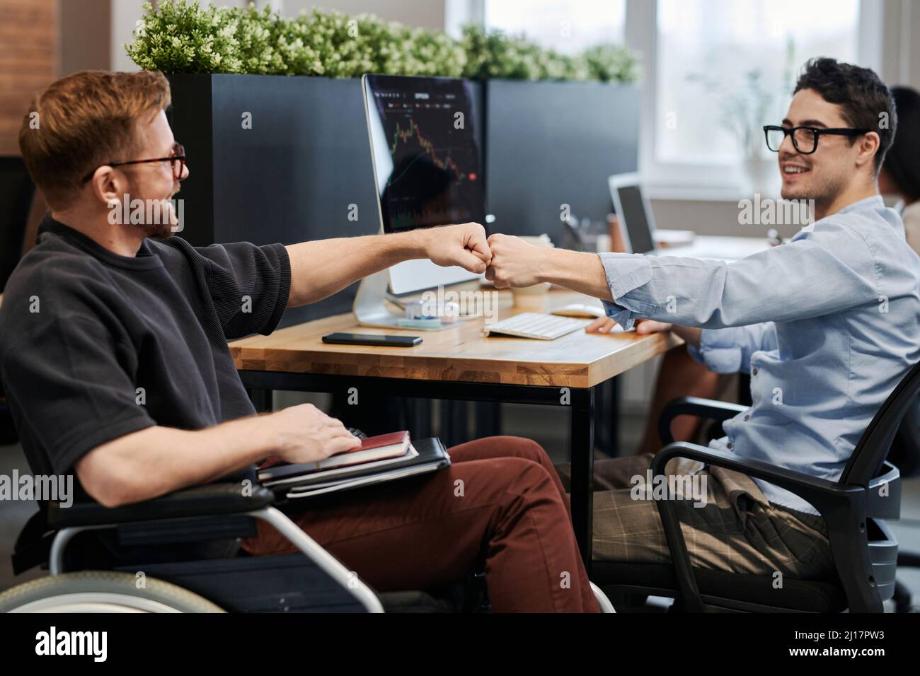 Disabled colleague greeting co-worker in office Stock Photo