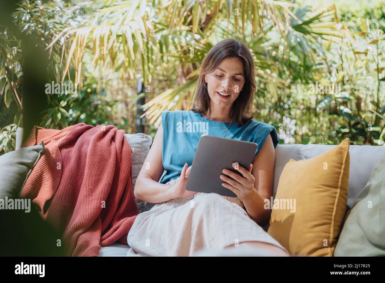 Businesswoman using tablet computer sitting on sofa Stock Photo