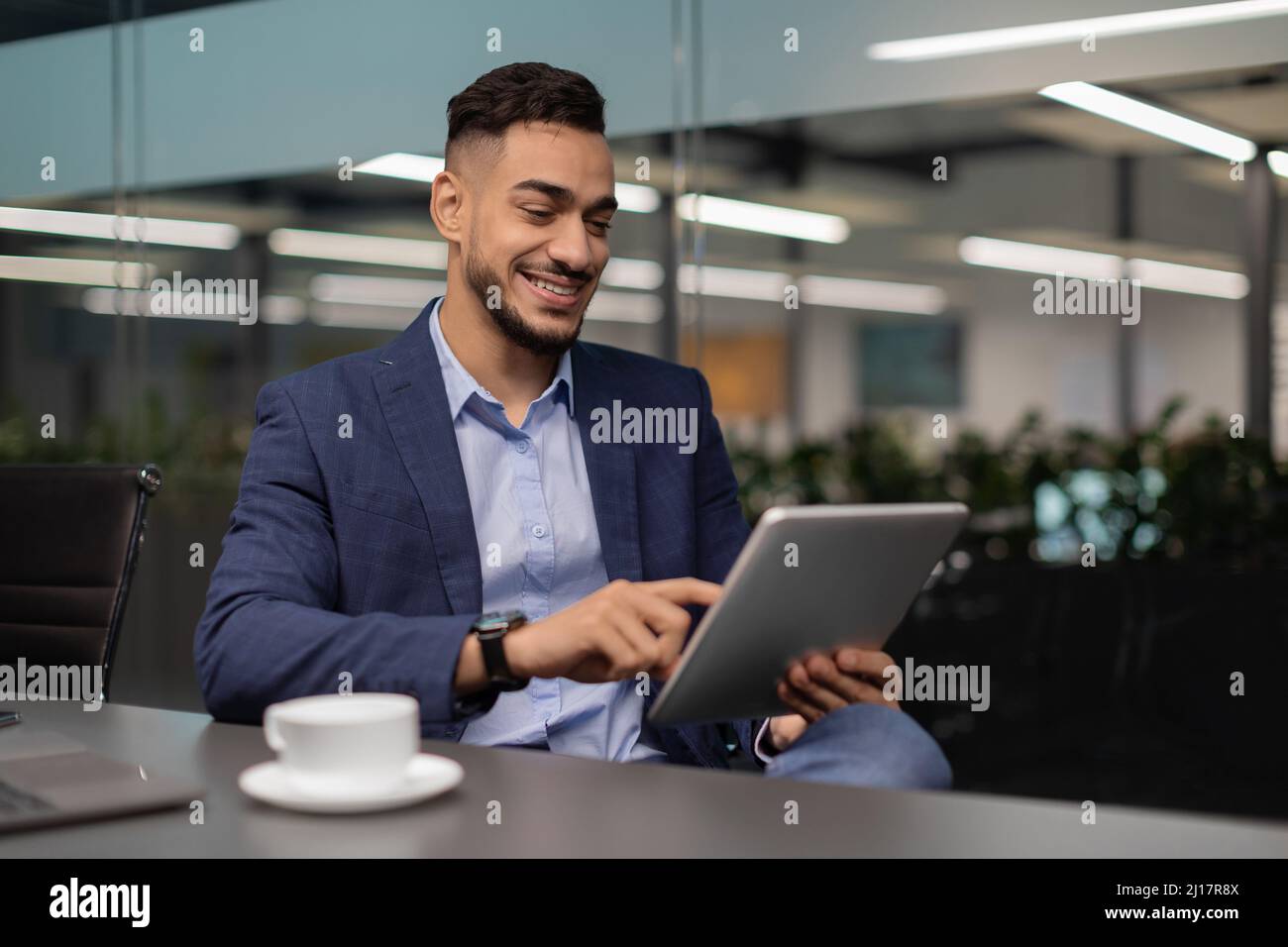 Happy middle eastern businessman working at office, using digital tablet Stock Photo