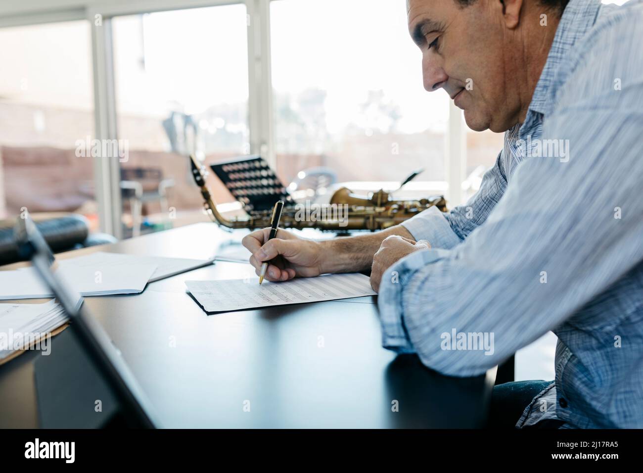 Man writing musical notes on paper sitting at table Stock Photo