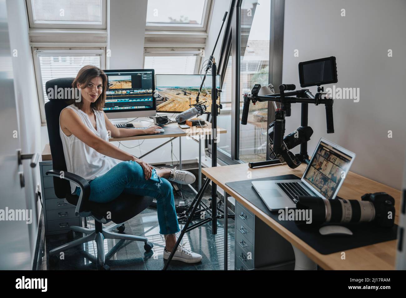 Photographer sitting on chair by desktop PC in studio Stock Photo