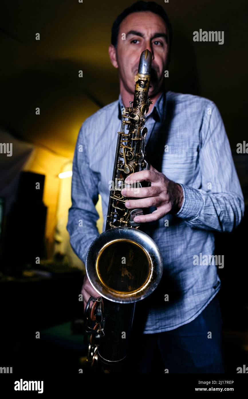 Saxophonist blowing saxophone practicing in recording studio Stock
