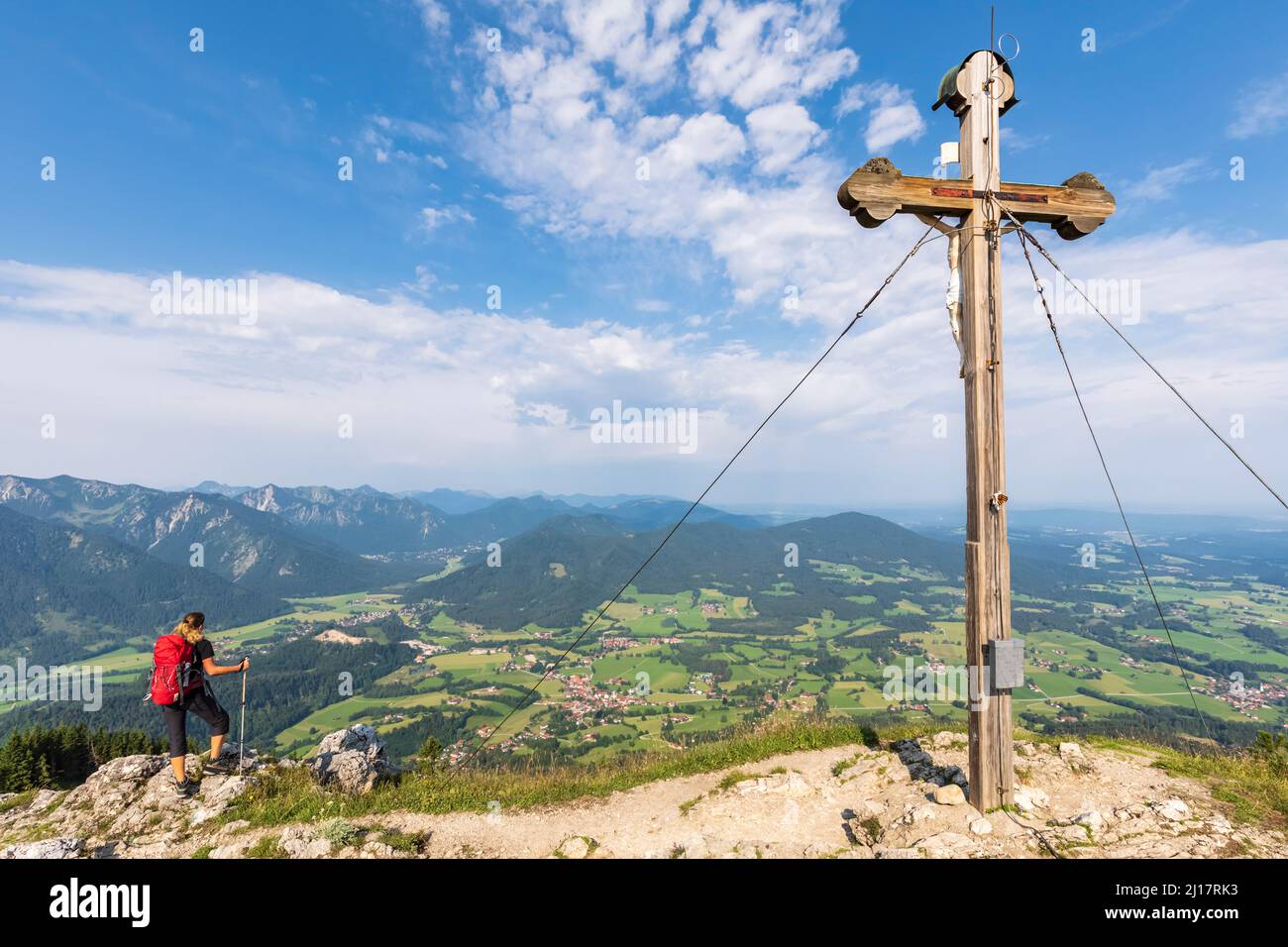 Female hiker admiring view from Bockstein with summit cross in foreground Stock Photo