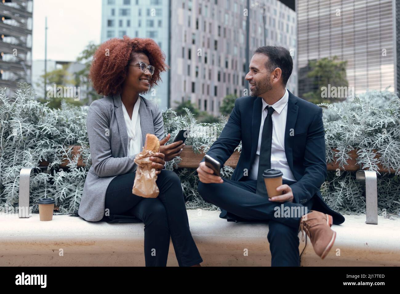 Two business colleagues talking while sitting outdoors Stock Photo