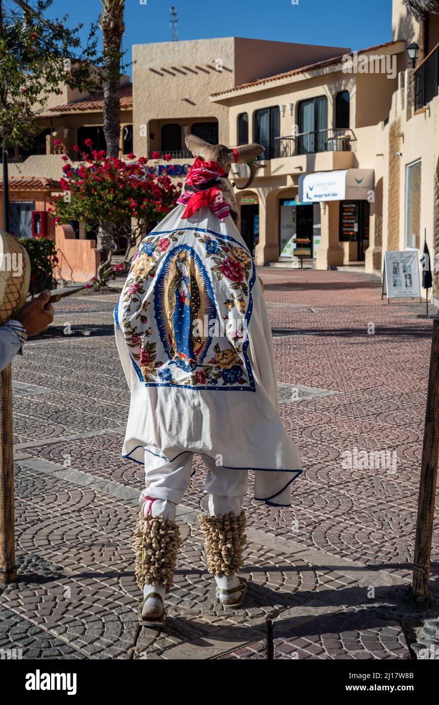 A Fariseo walks down a sidewalk in San Carlos, Sonora, Mexico, the image the Virgin Mary, Our Lady of Guadalupe, on his white robe. Stock Photo