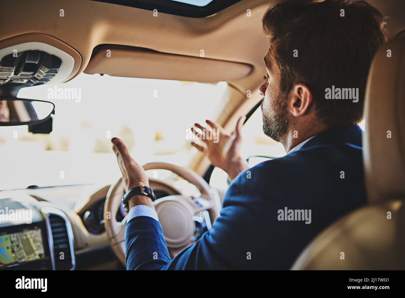 I cant believe how many cars are on the road. Shot of a stressed young businessman holding up his hands in frustration while driving in his car and Stock Photo