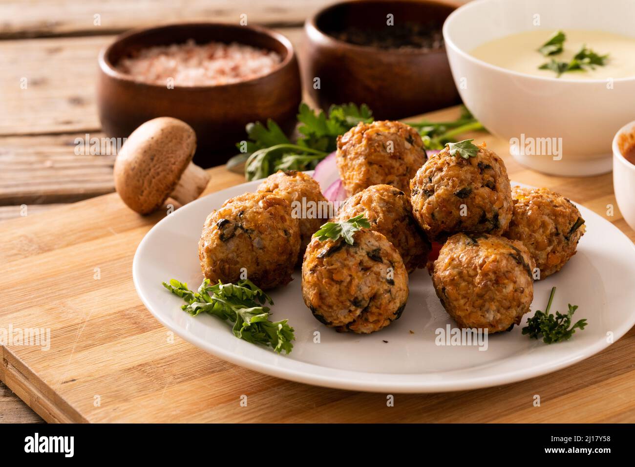 Close-up of fresh meatballs with edible mushroom and dip bowl on cutting board Stock Photo