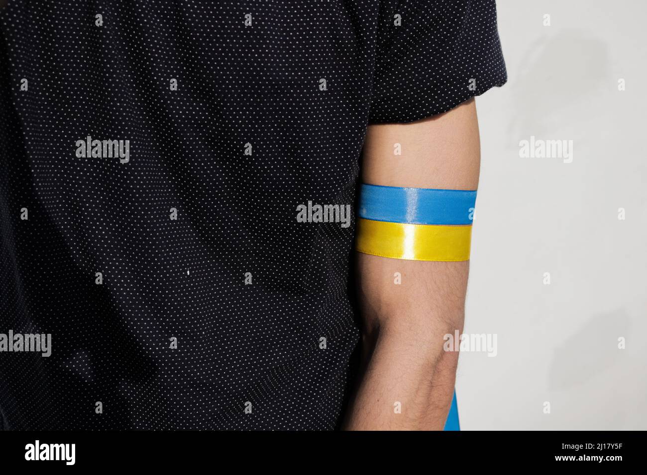 Ukrainian flag color ribbon tied on arm in support of Ukraine. Stock Photo