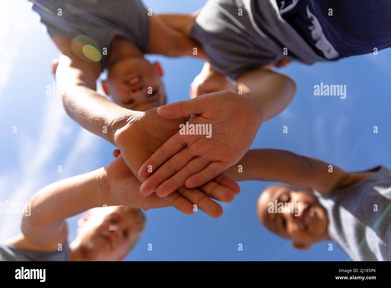 Directly below shot of multiracial elementary schoolboys stacking hands during soccer match Stock Photo
