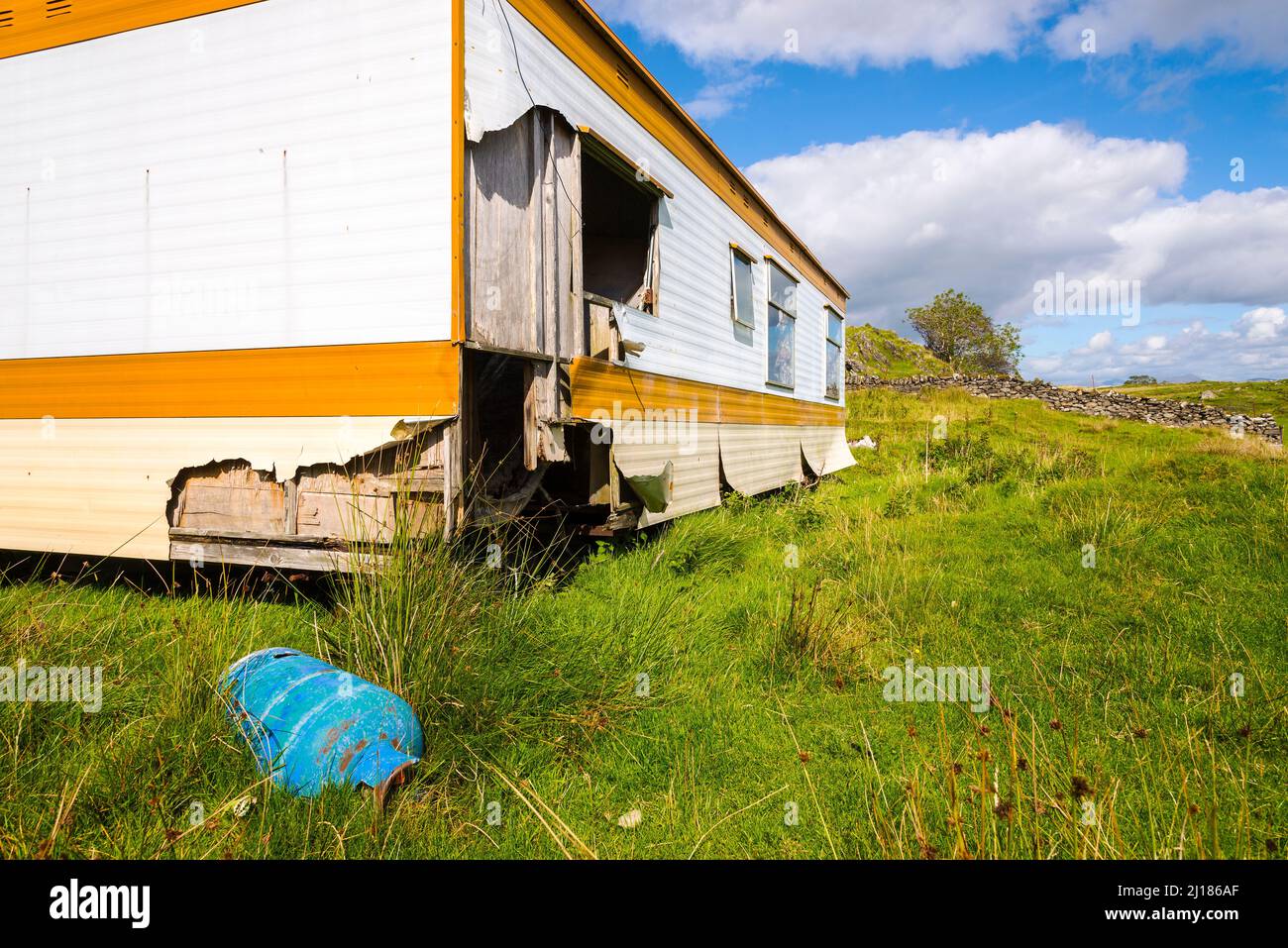 Sun shines on an old gas cannister and a derelict mobile home abandoned in the countryside on the island of Lismore in Scotland. Stock Photo