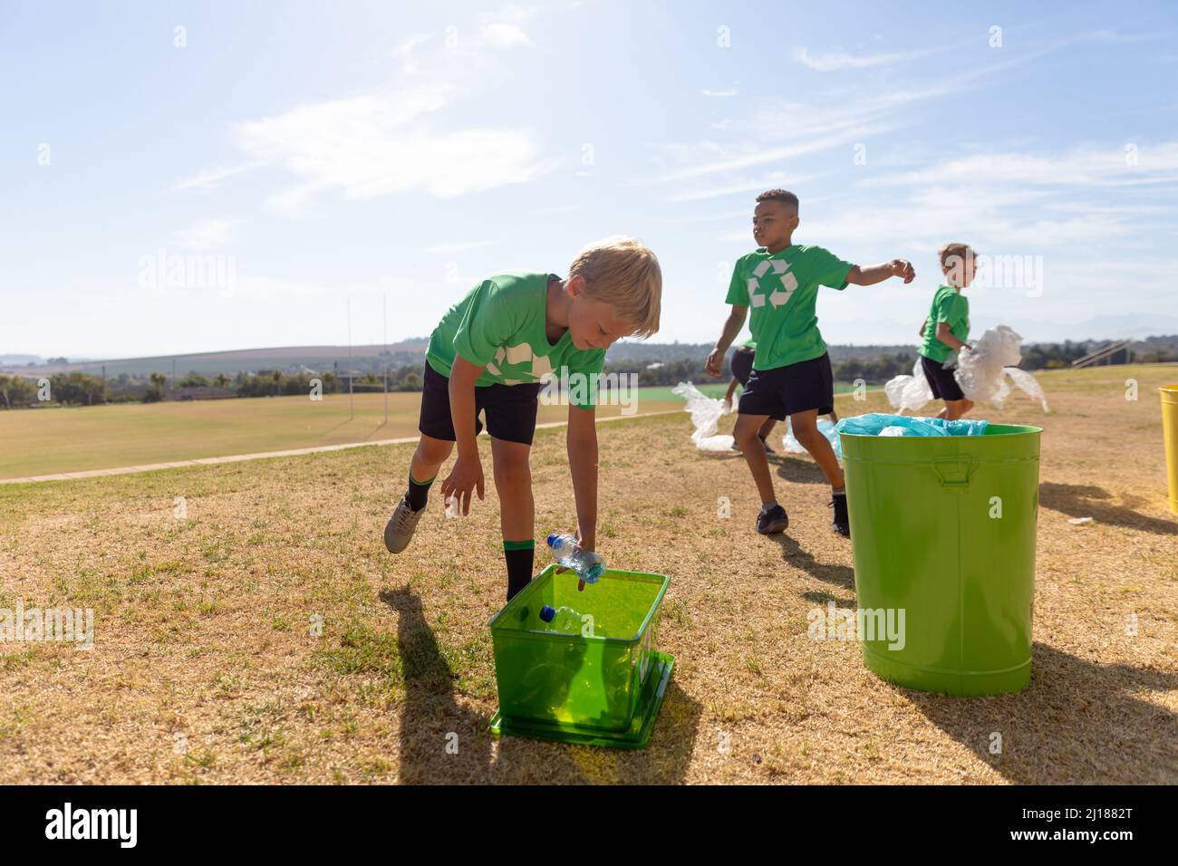 Multiracial elementary schoolboys putting plastic garbage in garbage