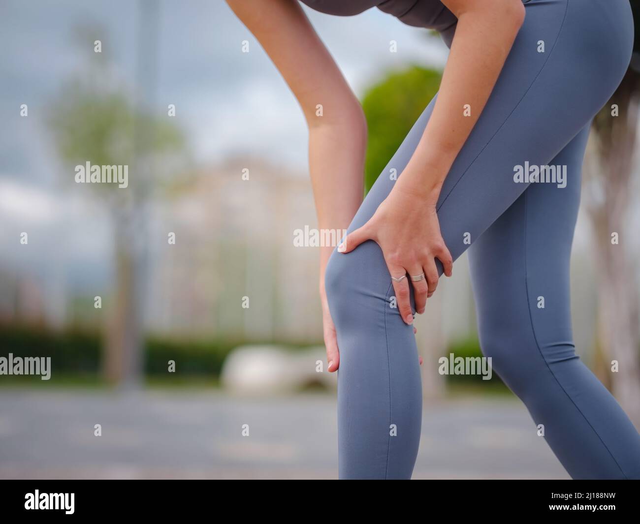 pain and from knee injury during morning run. Young woman