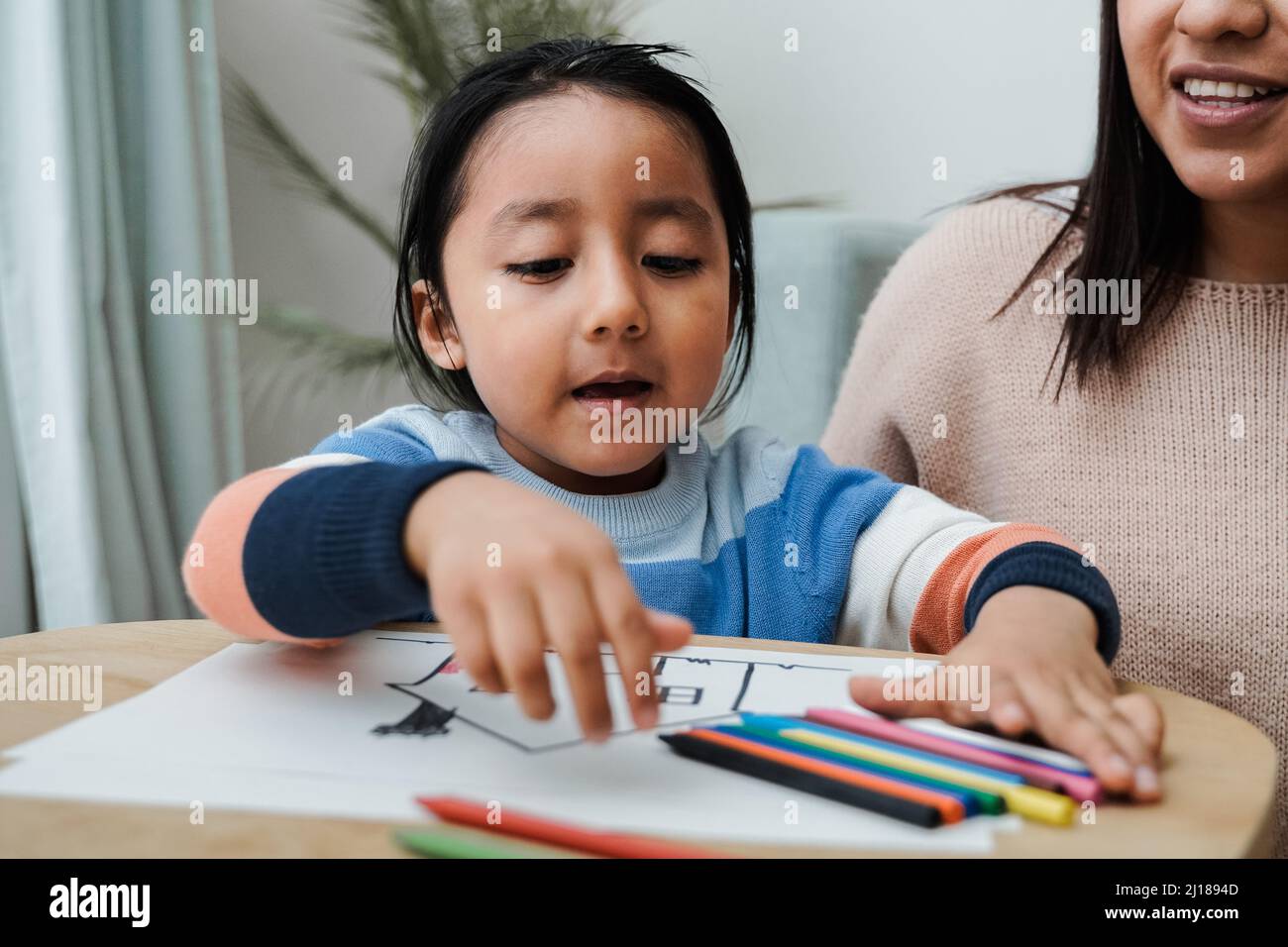 Happy latin american family having fun painting at home - Mother and son love concept - Focus on kid face Stock Photo
