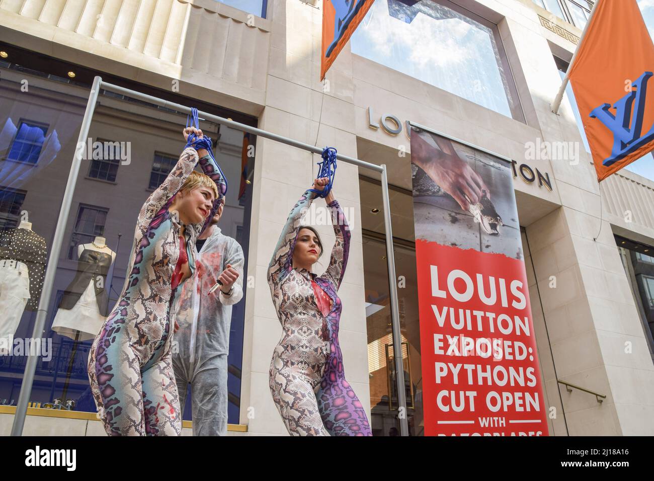 London, UK. 23rd March 2022. PETA activists wearing snake costumes and  covered in fake blood were 'skinned alive' outside the Louis Vuitton store  in New Bond Street in protest against the use