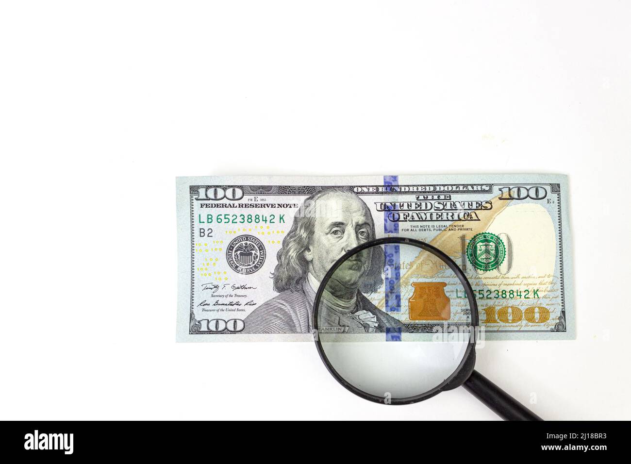 Magnifying glass on the background of a 100 dollars close-up. Magnifying Glass - 100 US Dollars Stock Photo