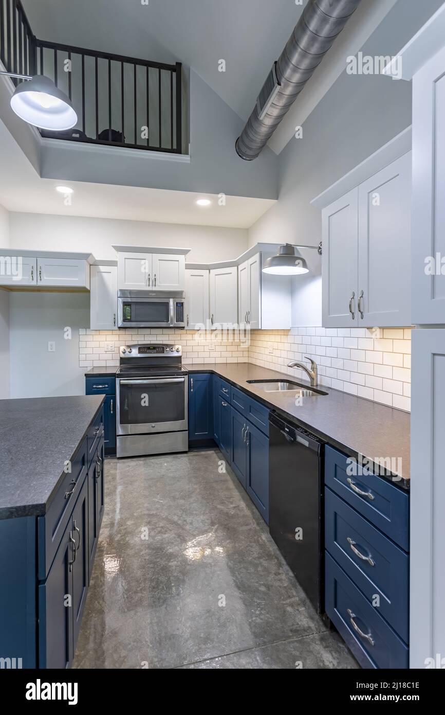 A vertical shot of a modern kitchen with blue counters and white cupboards Stock Photo