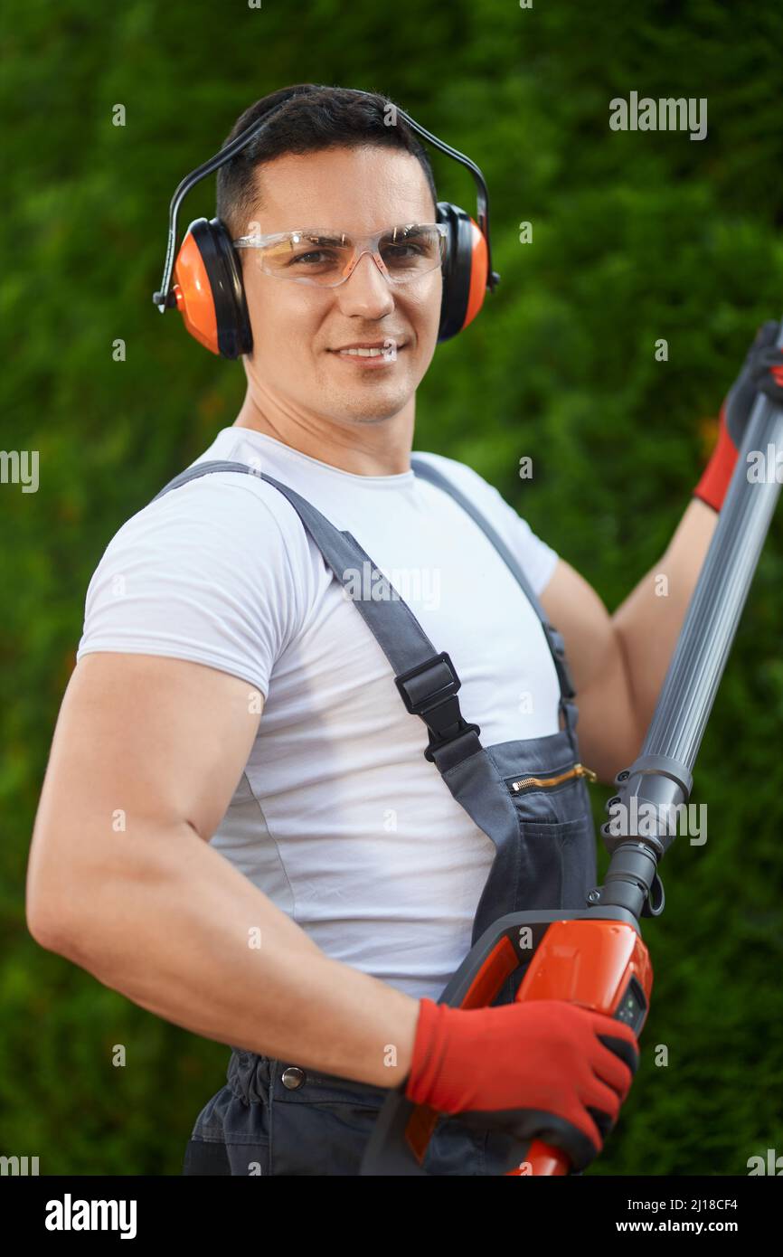 Portrait of strong male gardener in safety glasses, headphones and