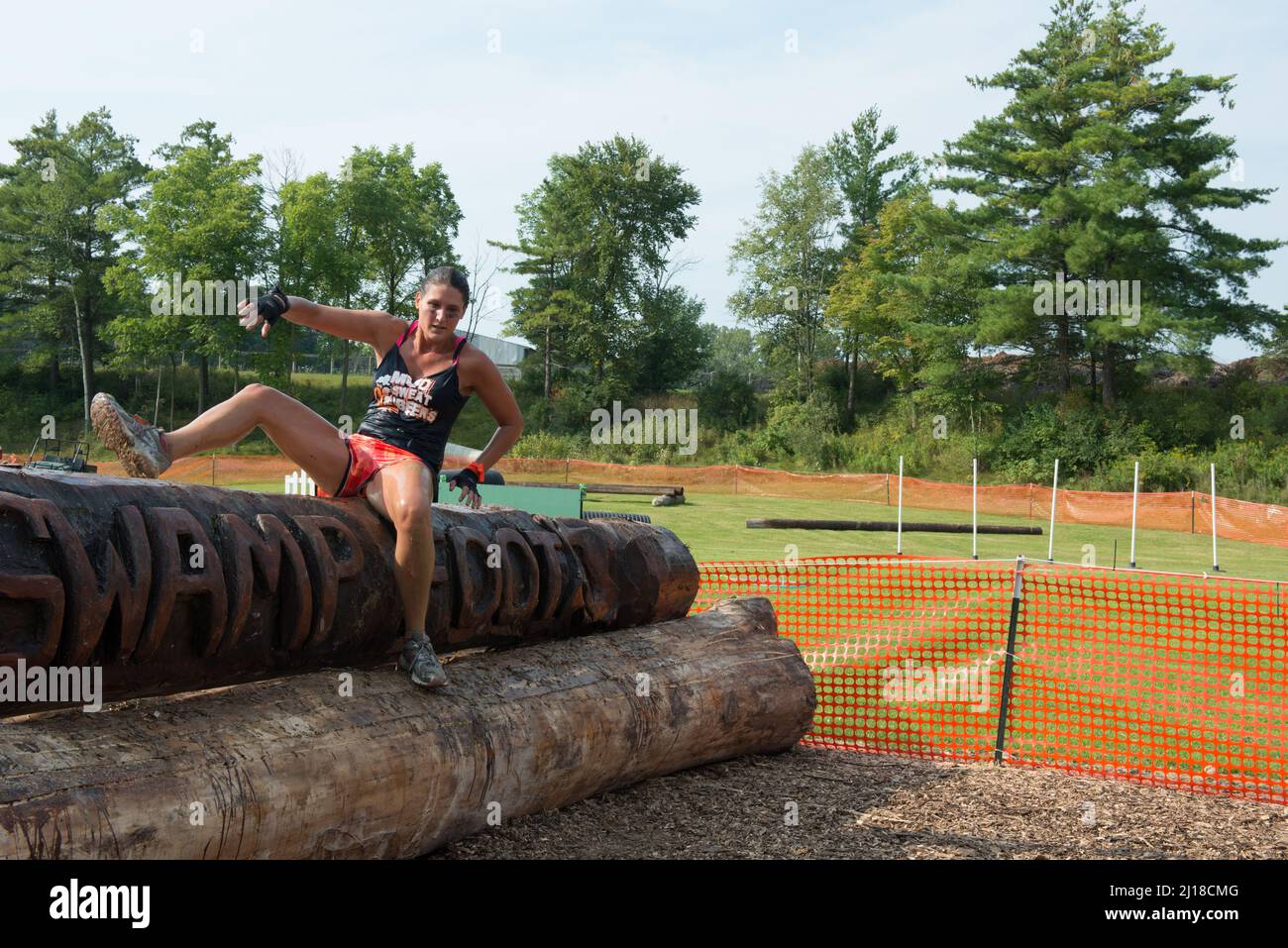 A female competitor makes her way over the log obstacle during the Swampfoot race in St. Clair, Michigan USA. Stock Photo