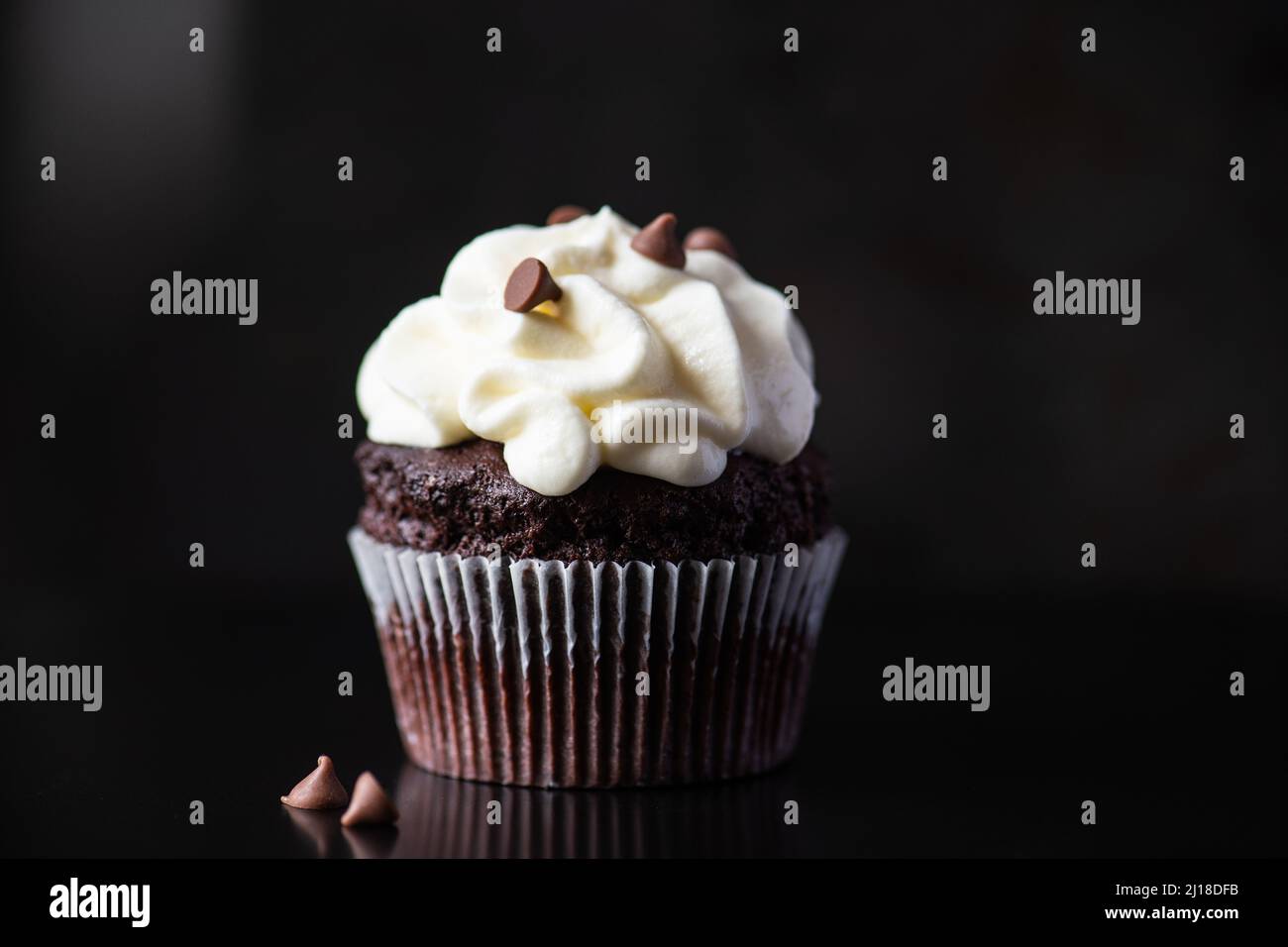 One chocolate cupcake with whipped cream frosting and chocolate chips. Stock Photo