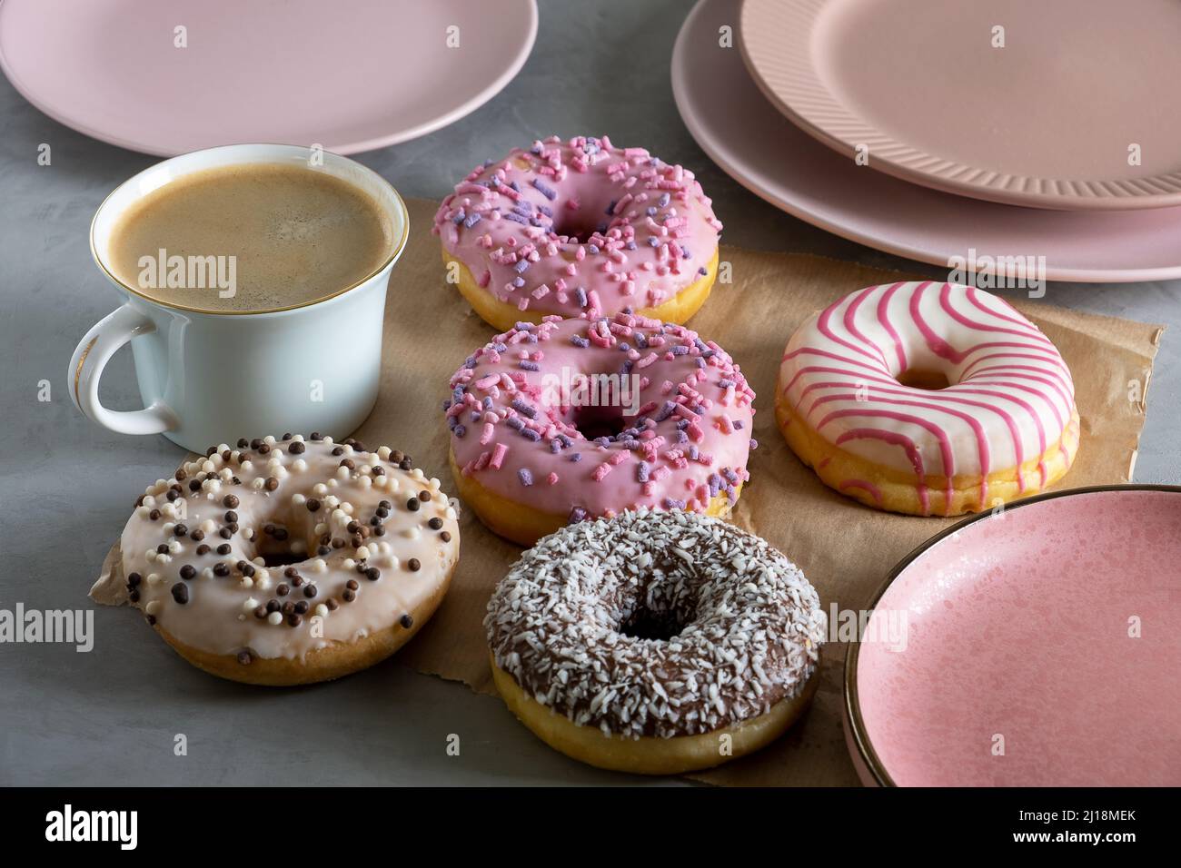 Several donuts lie on craft parchment paper on gray surface Stock Photo