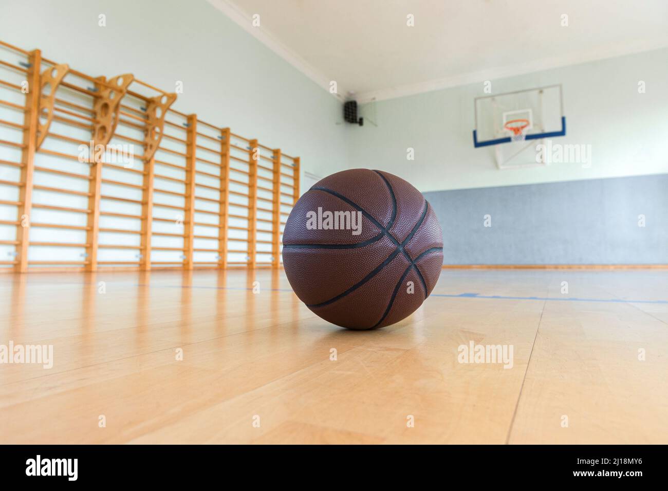 Basketball on hardwood court floor with natural lighting. Horizontal sport theme poster, greeting cards. Stock Photo