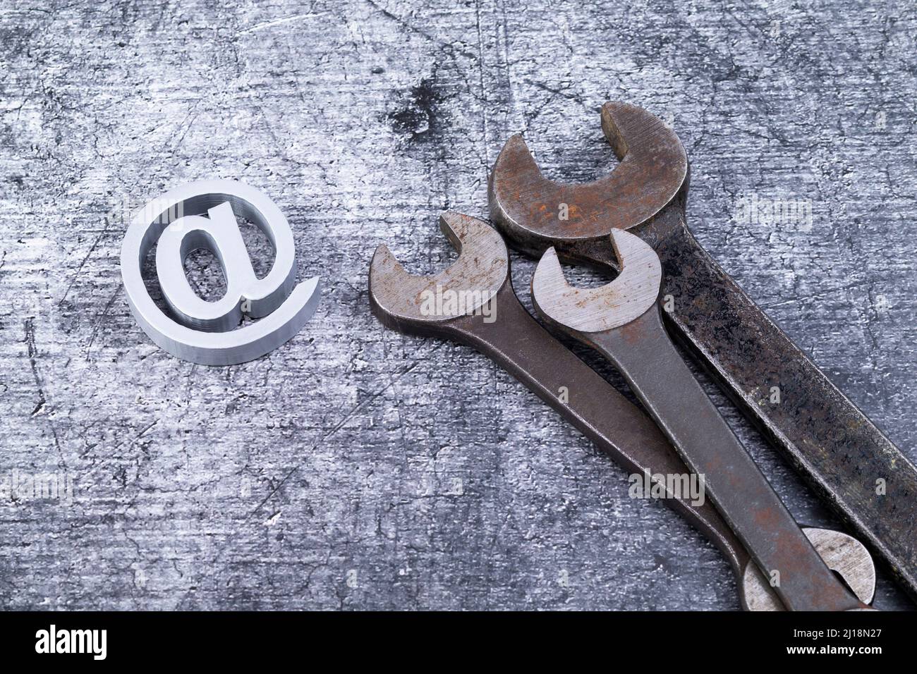 The photo shows various rusty wrenches on a gray background with a add sysmbol Stock Photo
