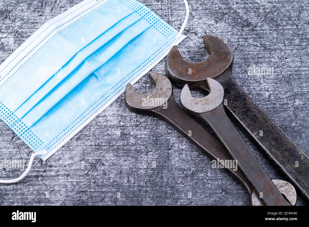 The photo shows various rusty wrenches on a gray background with a mouth mask Stock Photo