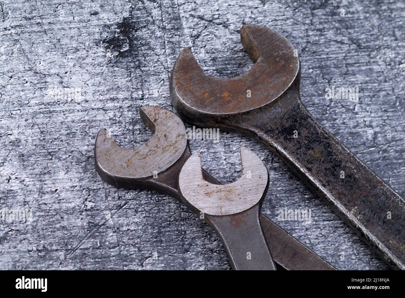 The photo shows various rusty wrenches on a gray background Stock Photo