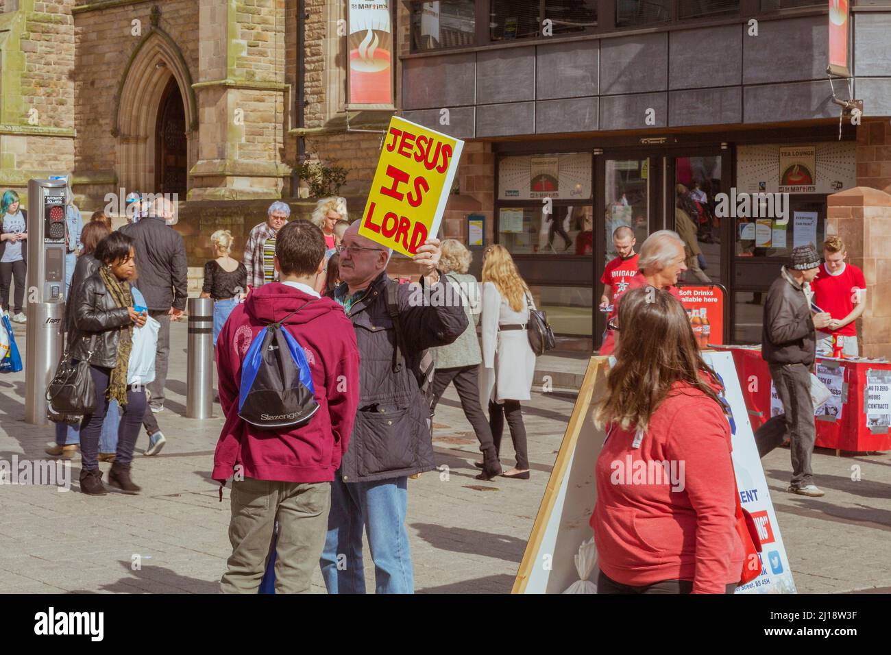 A street preacher holds up a sign saying Jesus is Lord in a busy city centre shopping area. Stock Photo