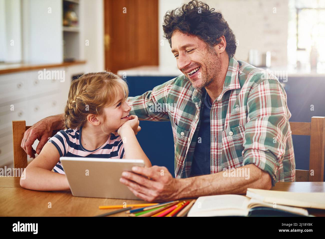 Youre really good at explaining stuff hey Dad. Cropped shot of a father helping his daughter complete her homework on a digital tablet. Stock Photo