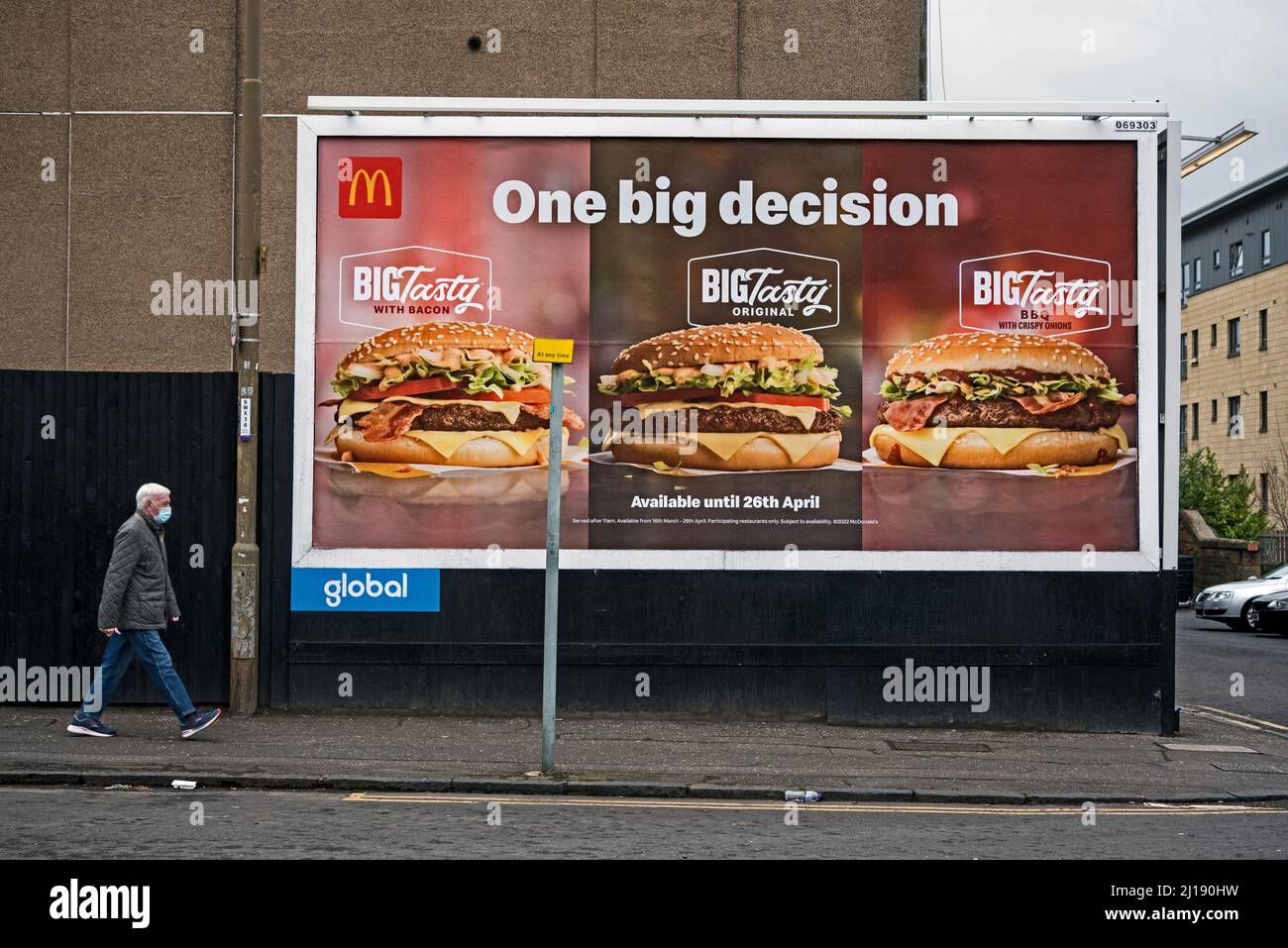Man walking on the street approaching a McDonalds advert on a billboard. Edinburgh, Scotland, UK. Stock Photo