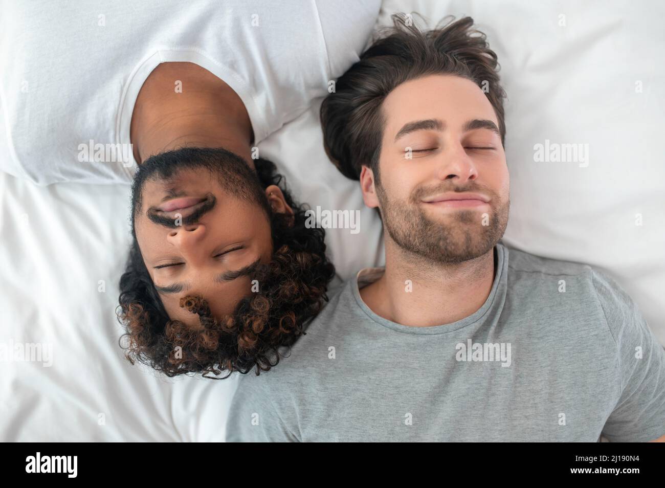 Young gay biracial couple sleeping in bed Stock Photo