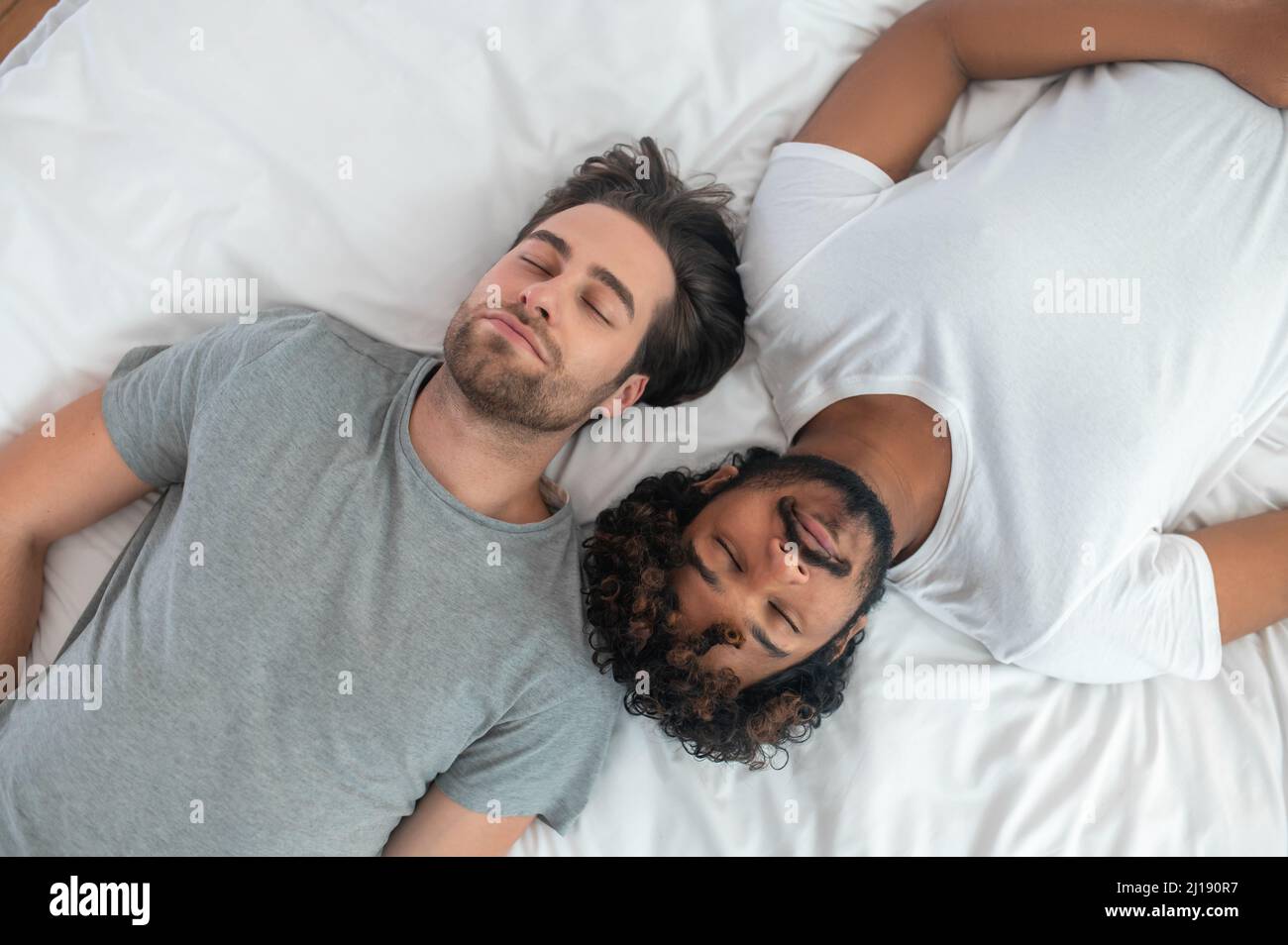 Two young men sleeping on their backs in bed Stock Photo
