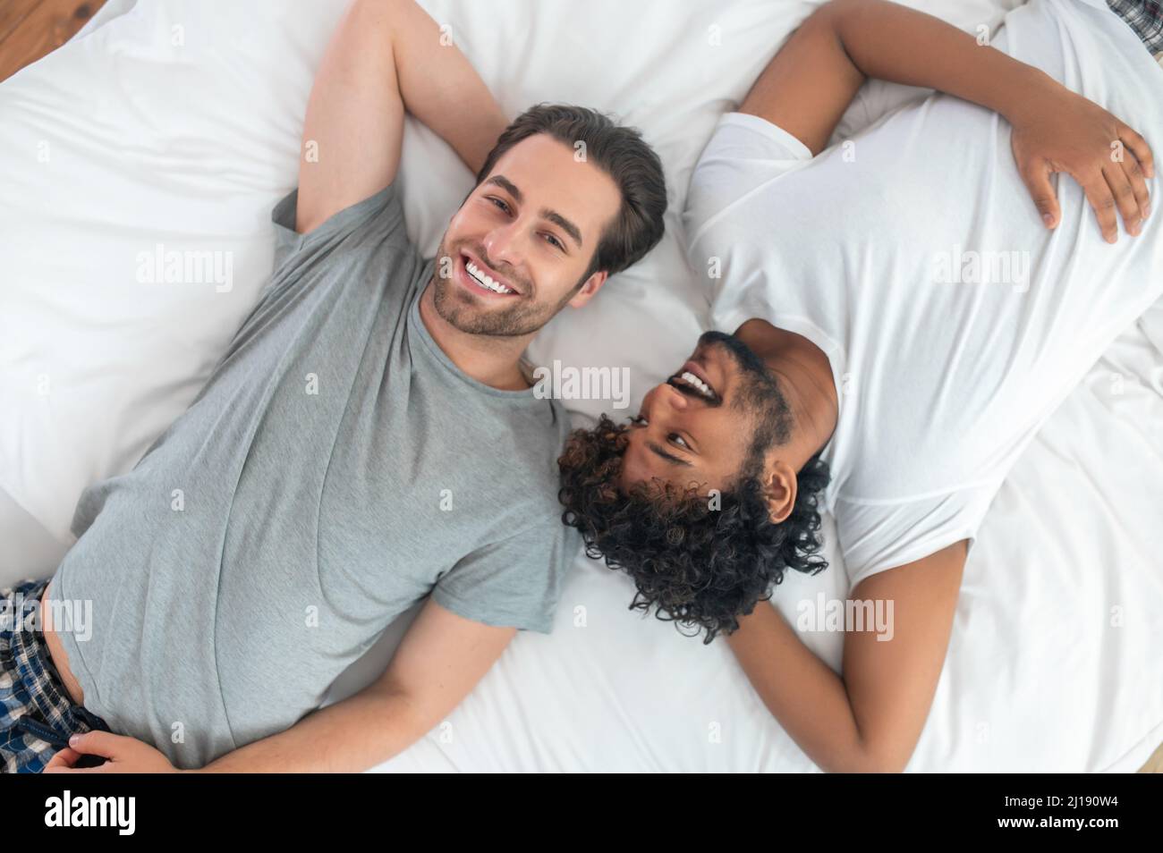 Romantic biracial gay couple resting in bed Stock Photo