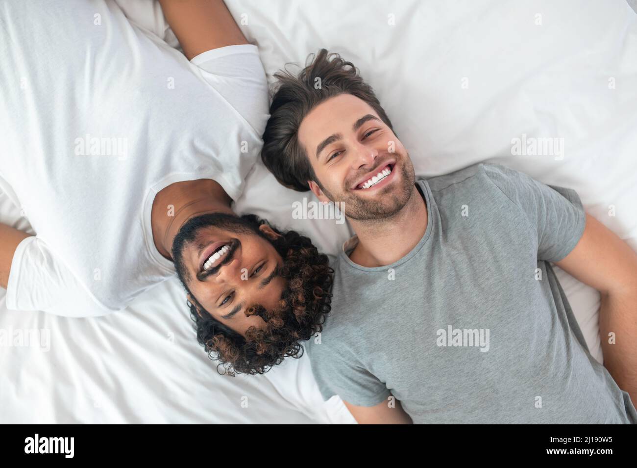 Happy gay couple posing for the camera in bed Stock Photo