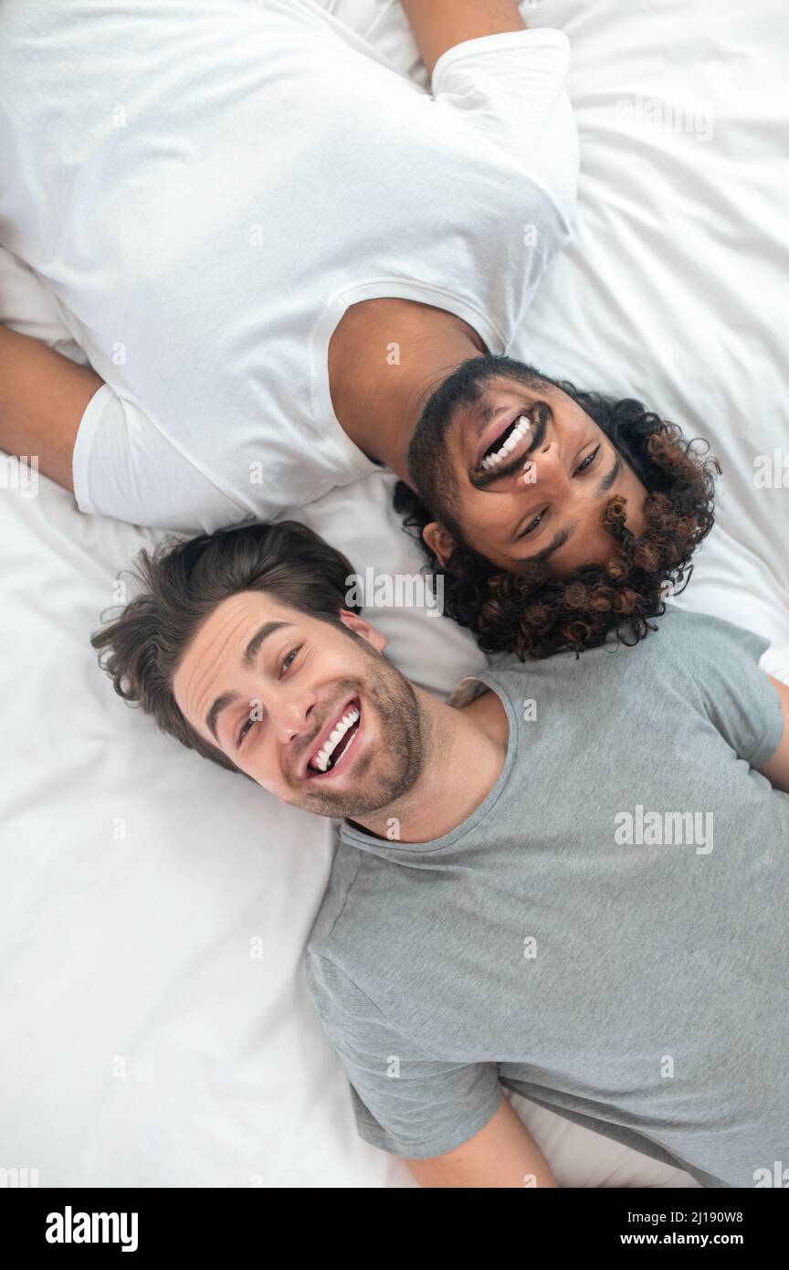Happy gay couple resting in their bed Stock Photo