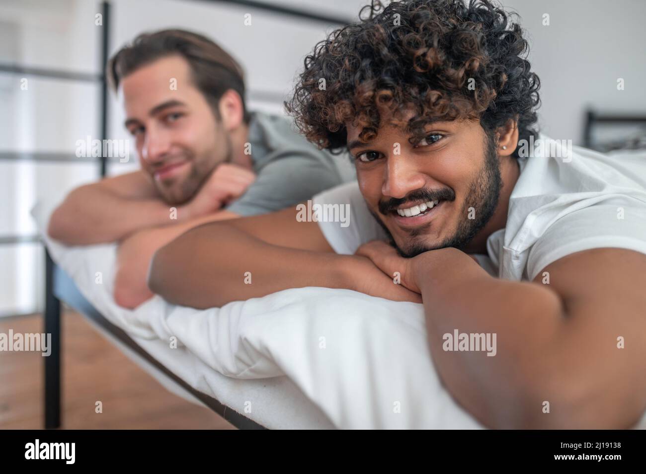 Young biracial gay couple lying in bed Stock Photo