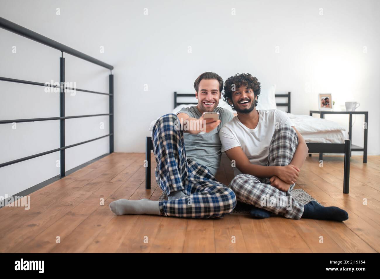 Two joyous men using the cellphone for channel-surfing Stock Photo