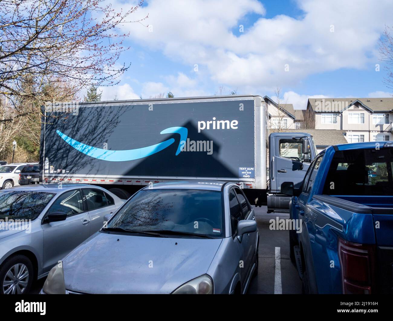 Seattle, WA USA - circa March 2022: Angled view of a large Amazon Prime semi-truck outside of an apartment complex on a bright, sunny day. Stock Photo