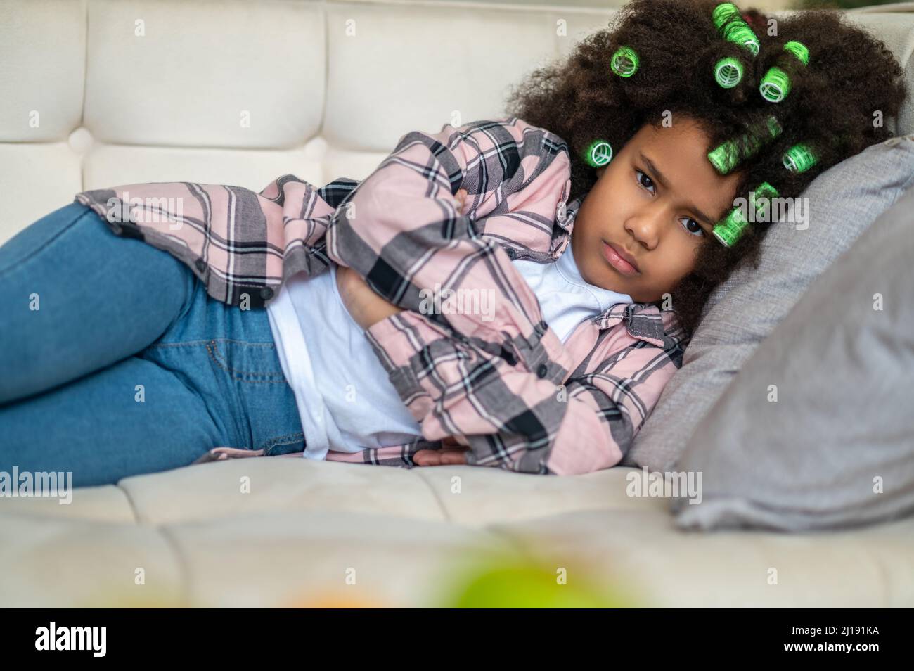 Frowning girl on sofa looking at camera Stock Photo